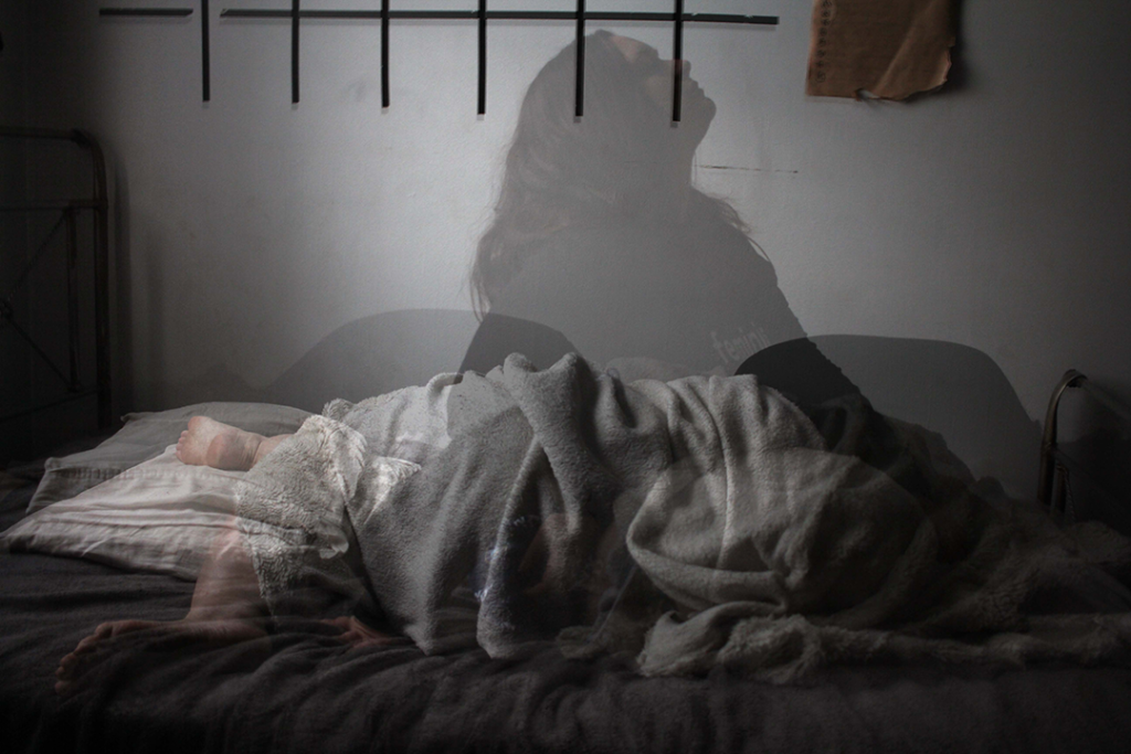A blurred, tired woman sitting up in bed